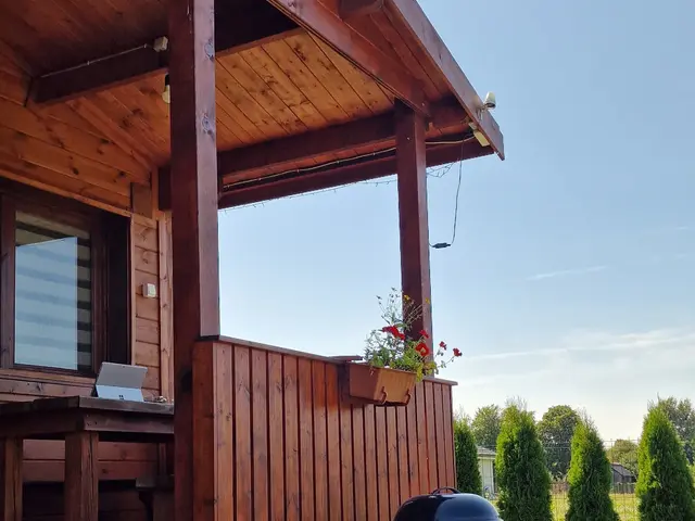 Zadaszony taras domku Na Roztoczu z wejściem do środka, obok grill