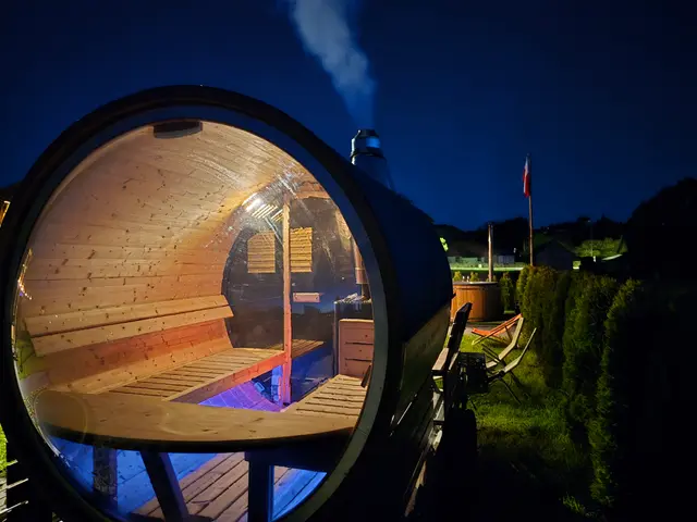 Rozgrzana sauna typu beczka po zmroku — rozświetlone wnętrze widoczne przez okno