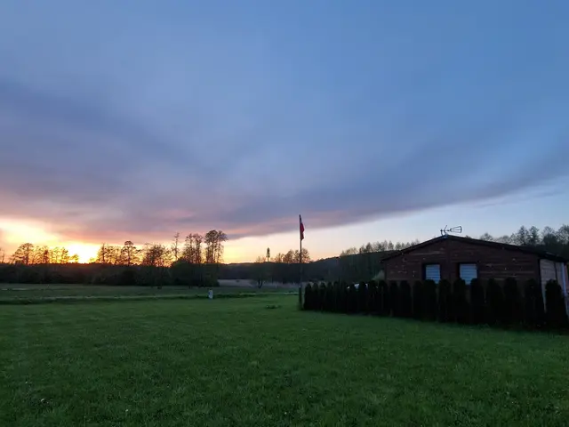 Domek Na Roztoczu o zmierzchu, widziany z drugiego końca łąki